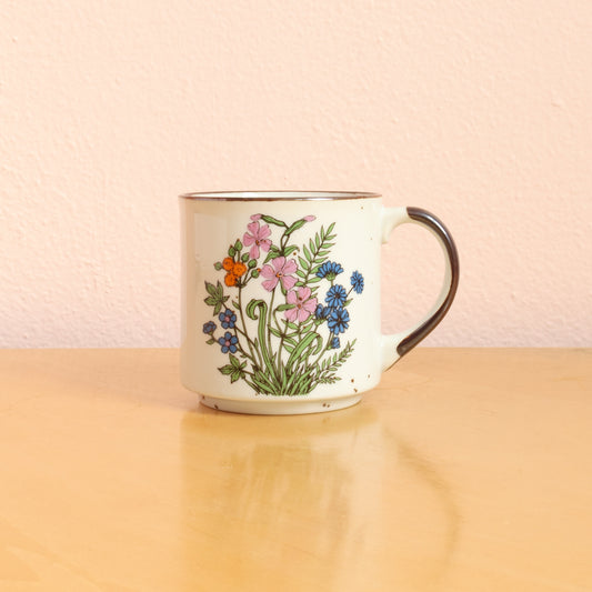 Vintage Japanese stoneware ceramic coffee mug with a brown handle and speckled glaze, bouquet of colorful  wildflowers on the front